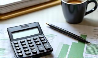 A calculator and financial documents on a desk.